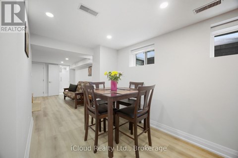A dining room with a table set for two with a vase of flowers on the table.