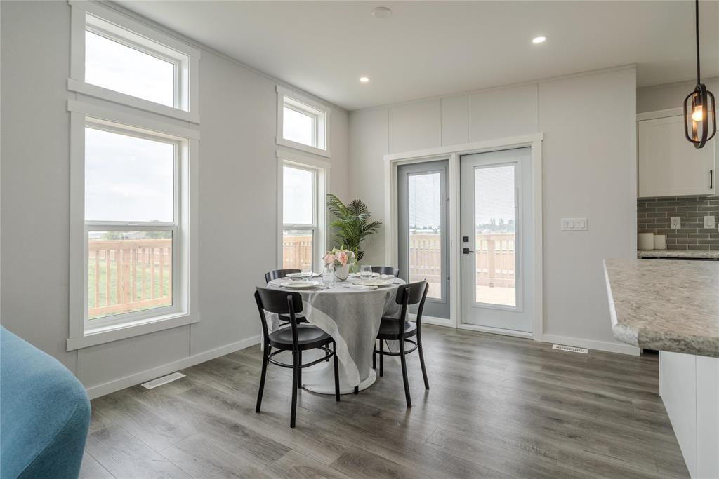 A dining room with a table set for two and a view of a deck outside the window.