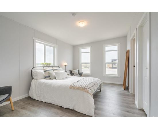A bedroom with a large bed and a chair.