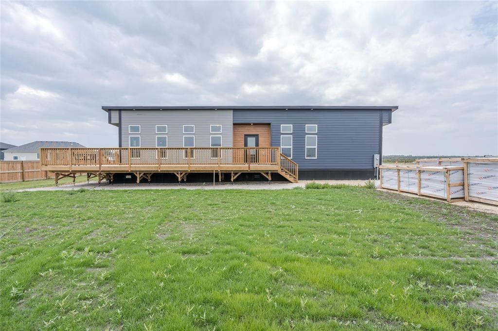 A modern house with a balcony overlooking a grassy area.