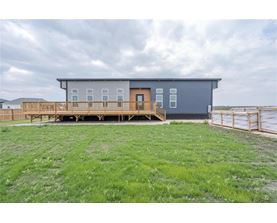 A modern house with a balcony overlooking a grassy area.