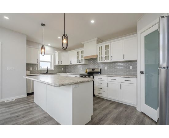 A kitchen with white cabinets and a marble countertop.