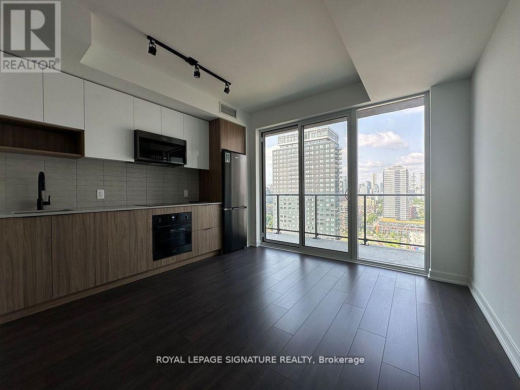 A spacious kitchen with dark wood floors and a view of the city.