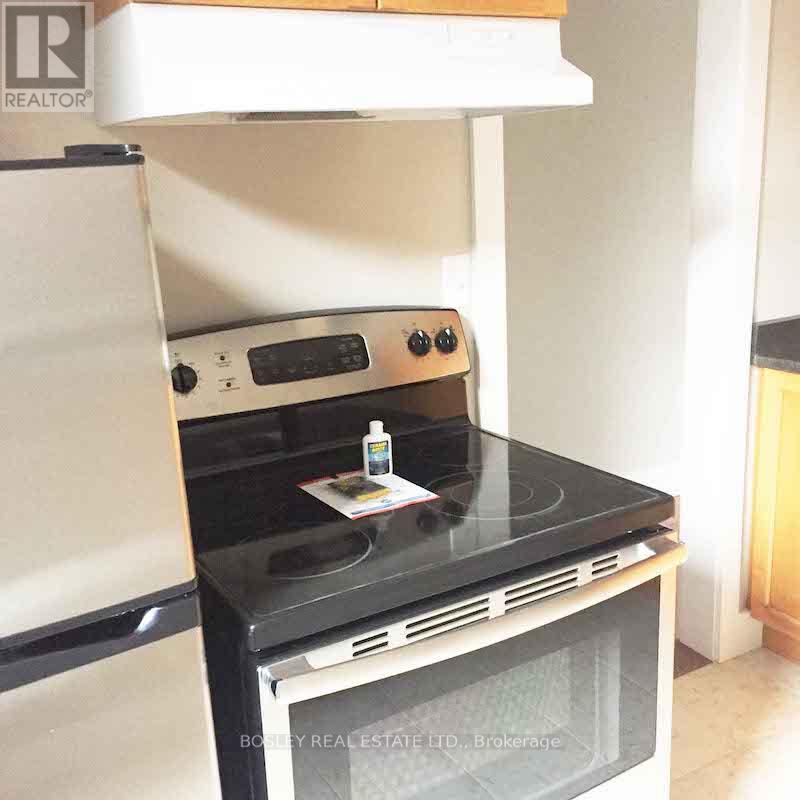 A black stove top oven with a white refrigerator in the background.