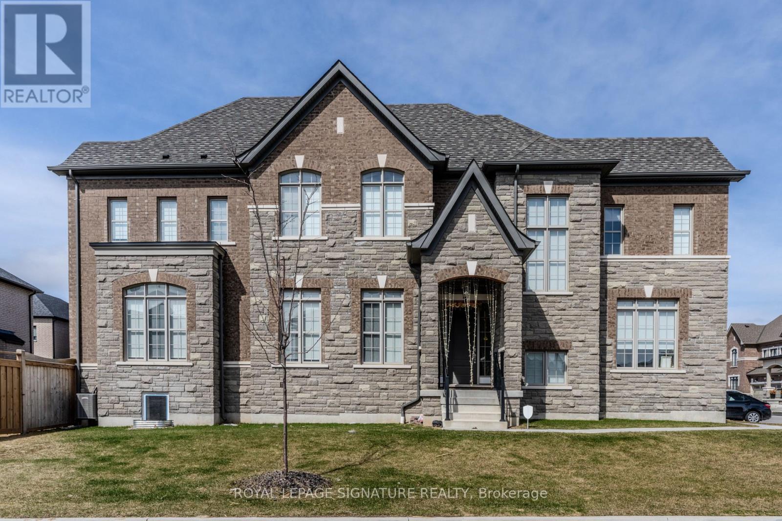 A large, well-maintained house with a stone facade and a large front yard.