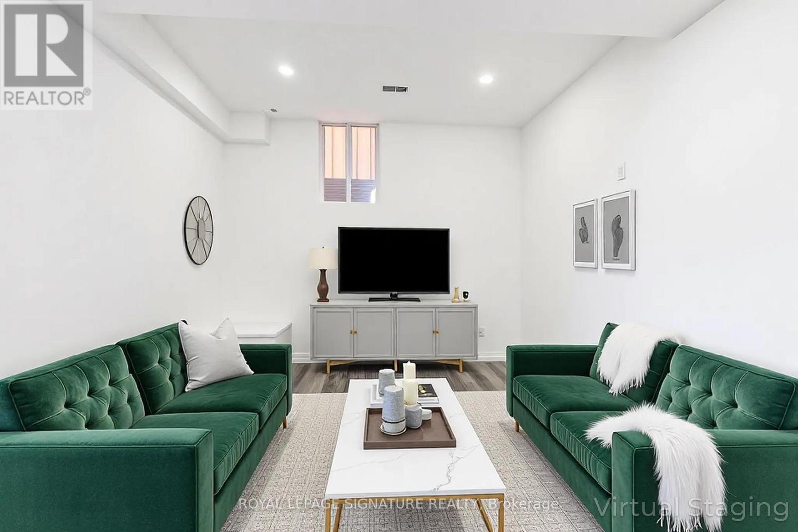 A living room with green velvet sofas and a white coffee table.