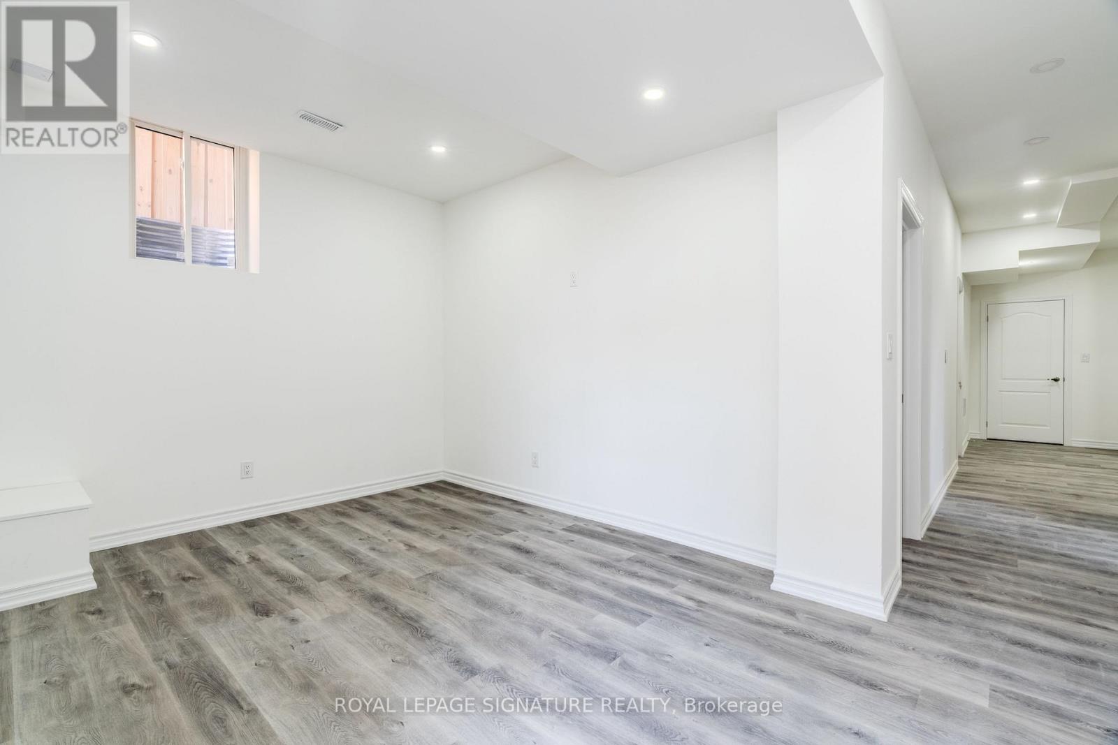 A spacious room with wooden flooring and white walls.