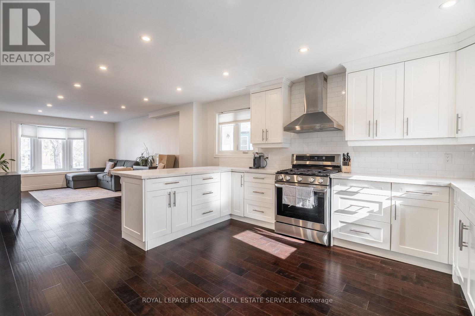 A spacious kitchen with white cabinets and a wood floor.