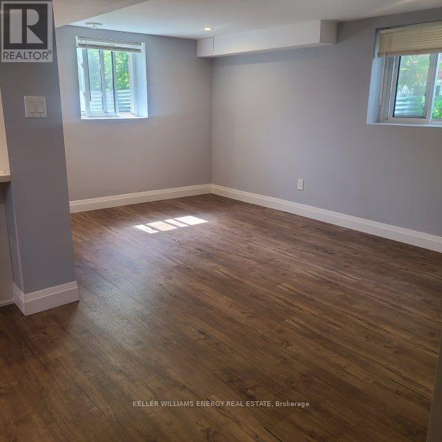 A room with wooden flooring and two windows.