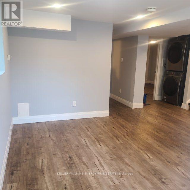 A room with wooden flooring and a washing machine in the corner.