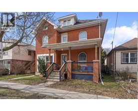 A red brick house with a blue railing on the front porch.