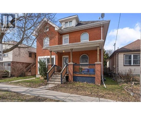 A red brick house with a blue railing on the front porch.
