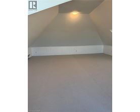 A spacious attic room with a skylight and a hanging light fixture.