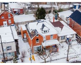 A snow-covered residential area with houses and a street sign.