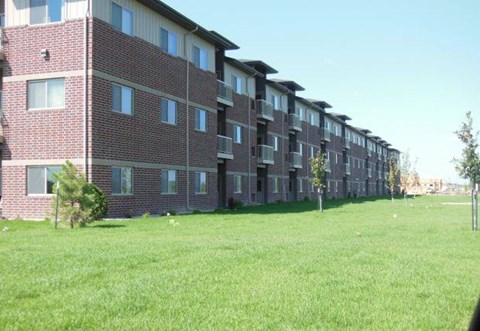 a brick apartment building with green grass in front of it