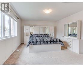 A bedroom with a bed, dresser, and mirror.