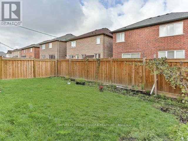 A backyard with a wooden fence and green grass.