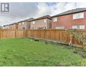 A backyard with a wooden fence and green grass.