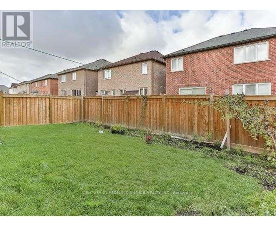 A backyard with a wooden fence and green grass.