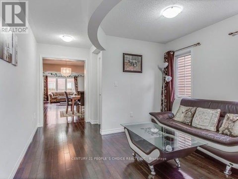 A living room with a couch, coffee table, and a painting on the wall.