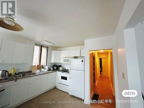 A white kitchen with a refrigerator, sink, and stove.