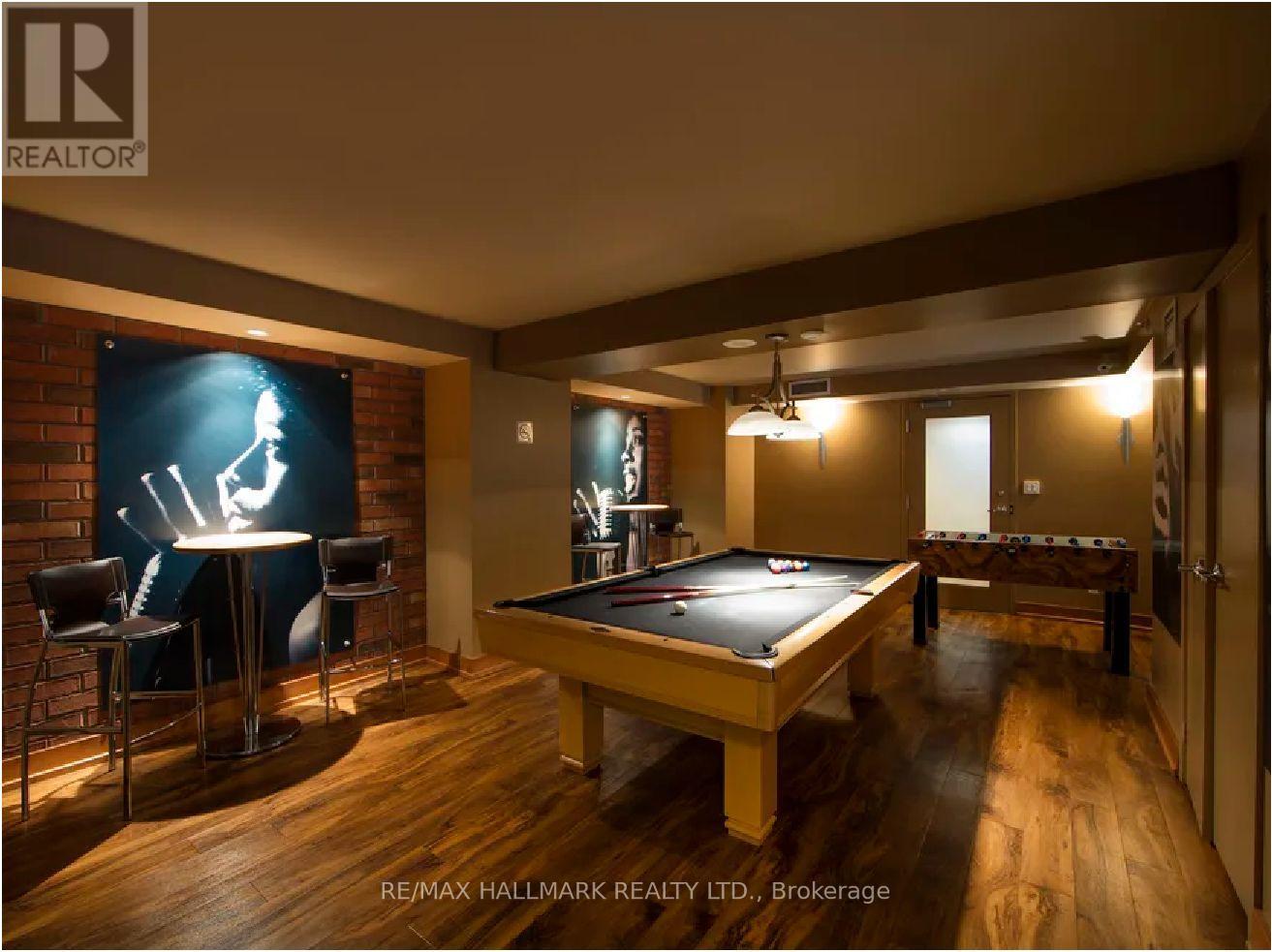 A pool table is in the middle of a room with a bar and a television.