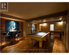A pool table is in the middle of a room with a bar and a television.