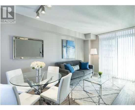 A modern living room with a glass table and white chairs.
