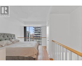 A bedroom with a large bed and a view of a balcony with buildings outside.