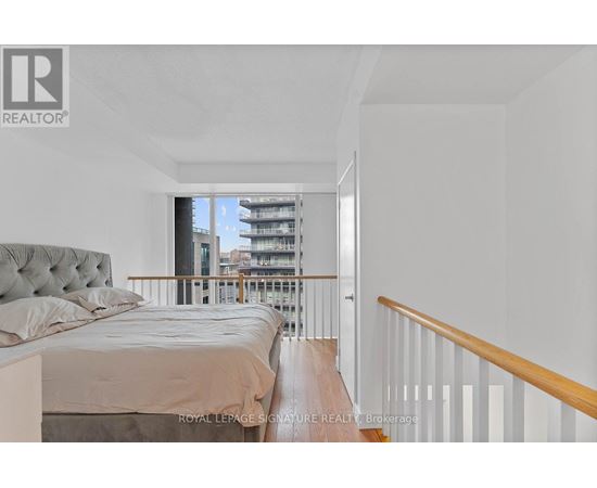 A bedroom with a large bed and a view of a balcony with buildings outside.