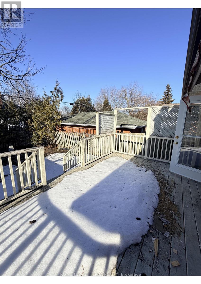 A snow-covered deck with a white railing and a green roofed building in the background.