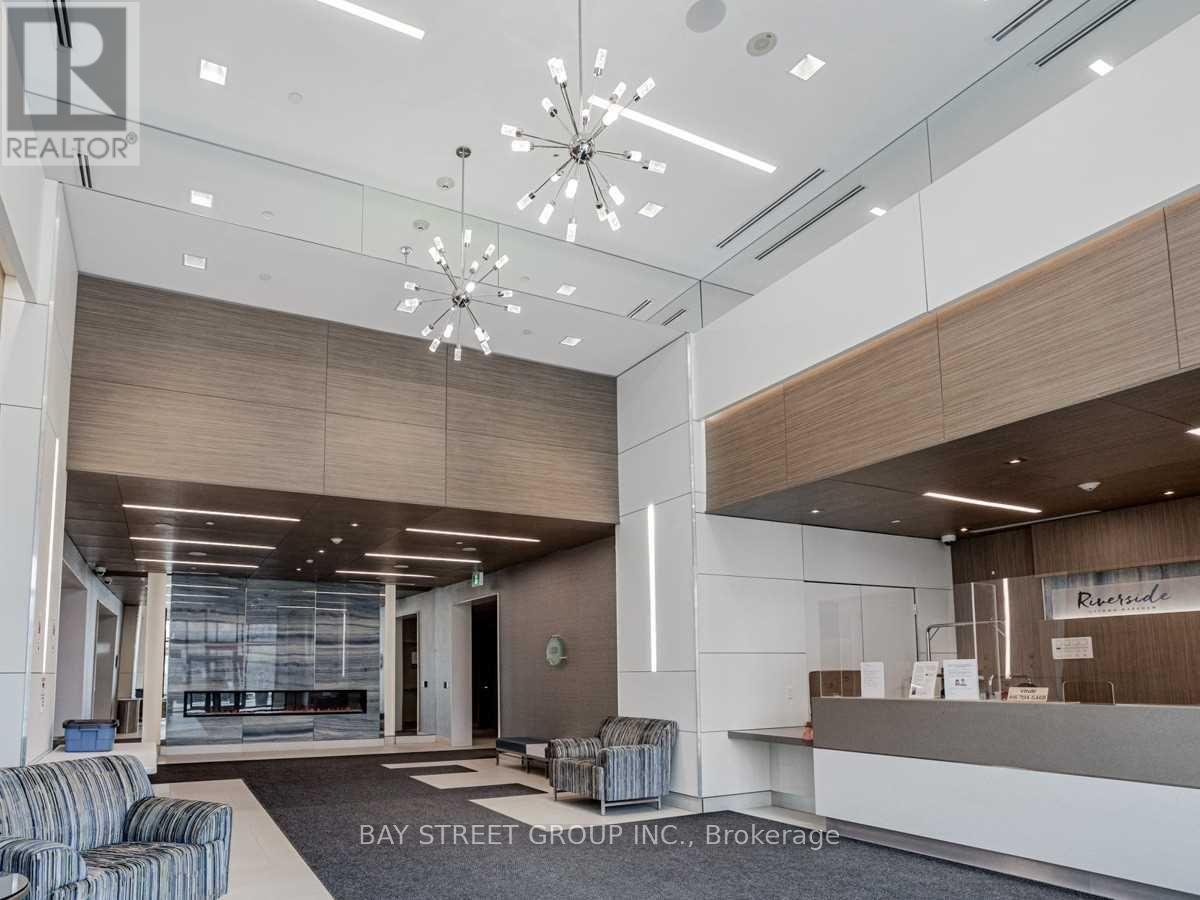 A modern office lobby with a reception desk and a large chandelier.