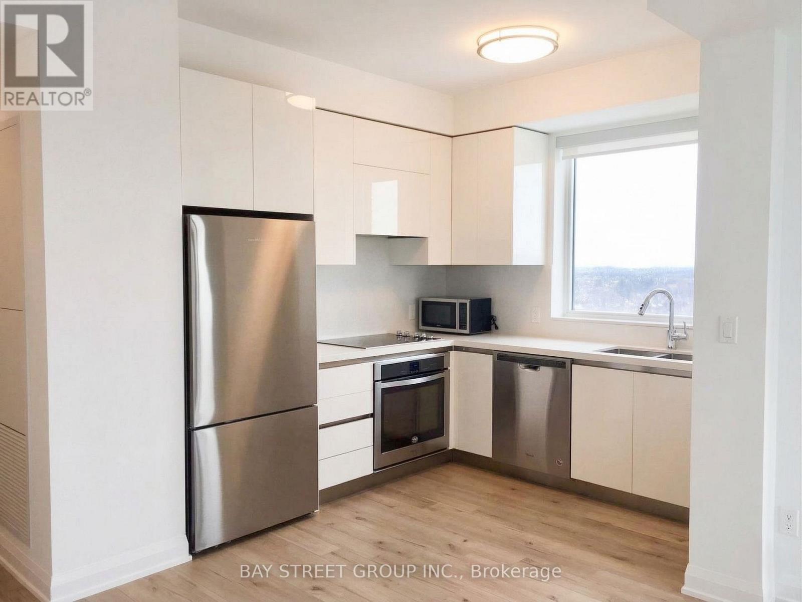 A modern kitchen with a stainless steel refrigerator and white cabinets.