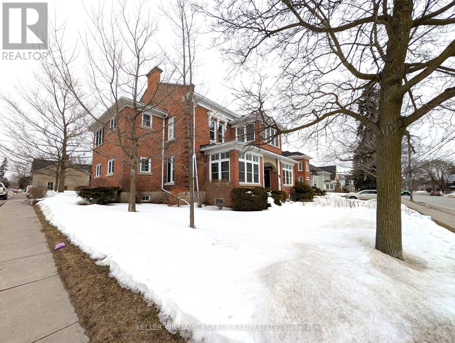 A brick house with snow on the ground and a tree in front.