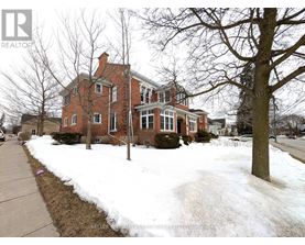 A brick house with snow on the ground and a tree in front.