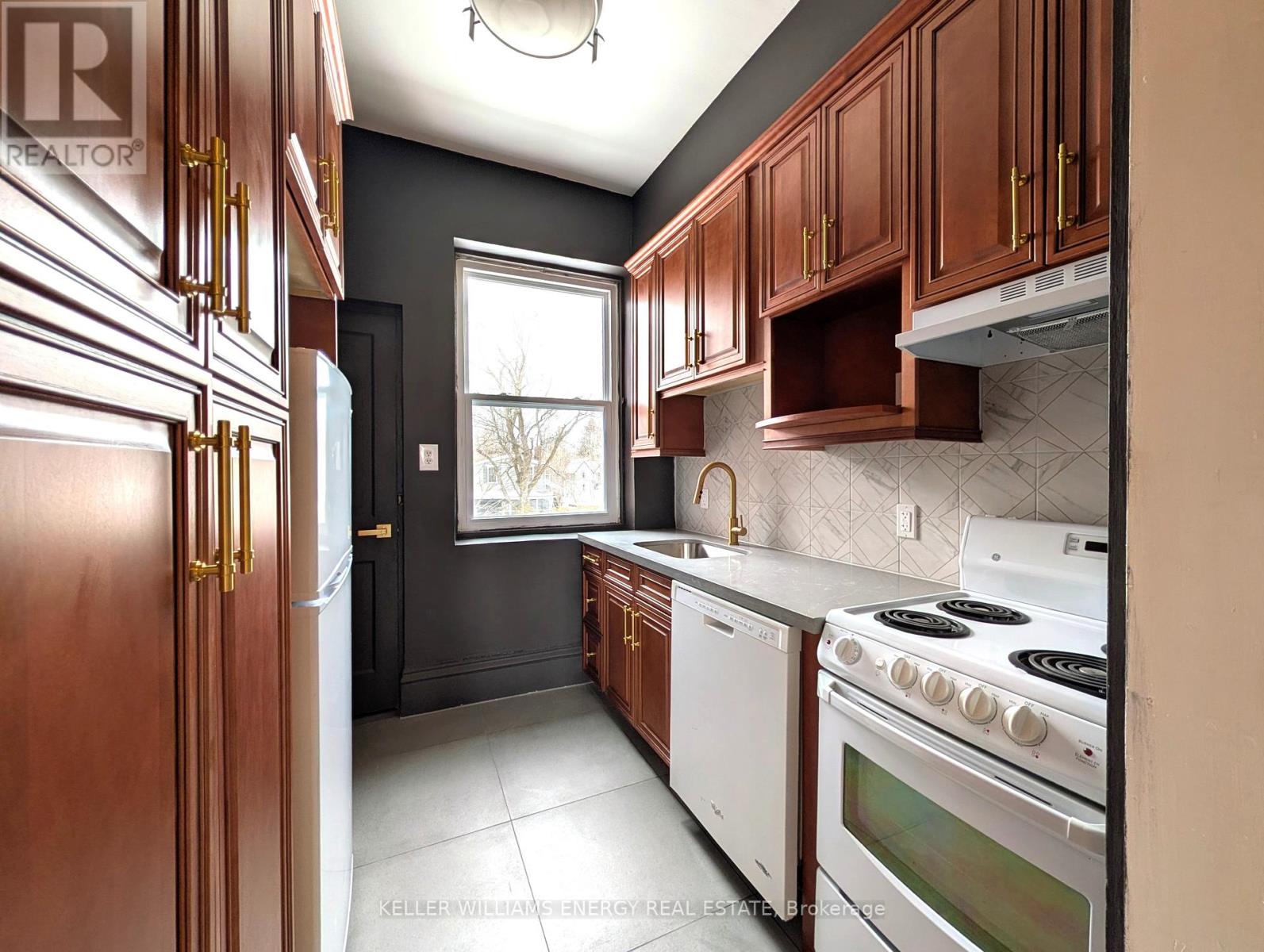 A kitchen with a white stove top oven and a white dishwasher.