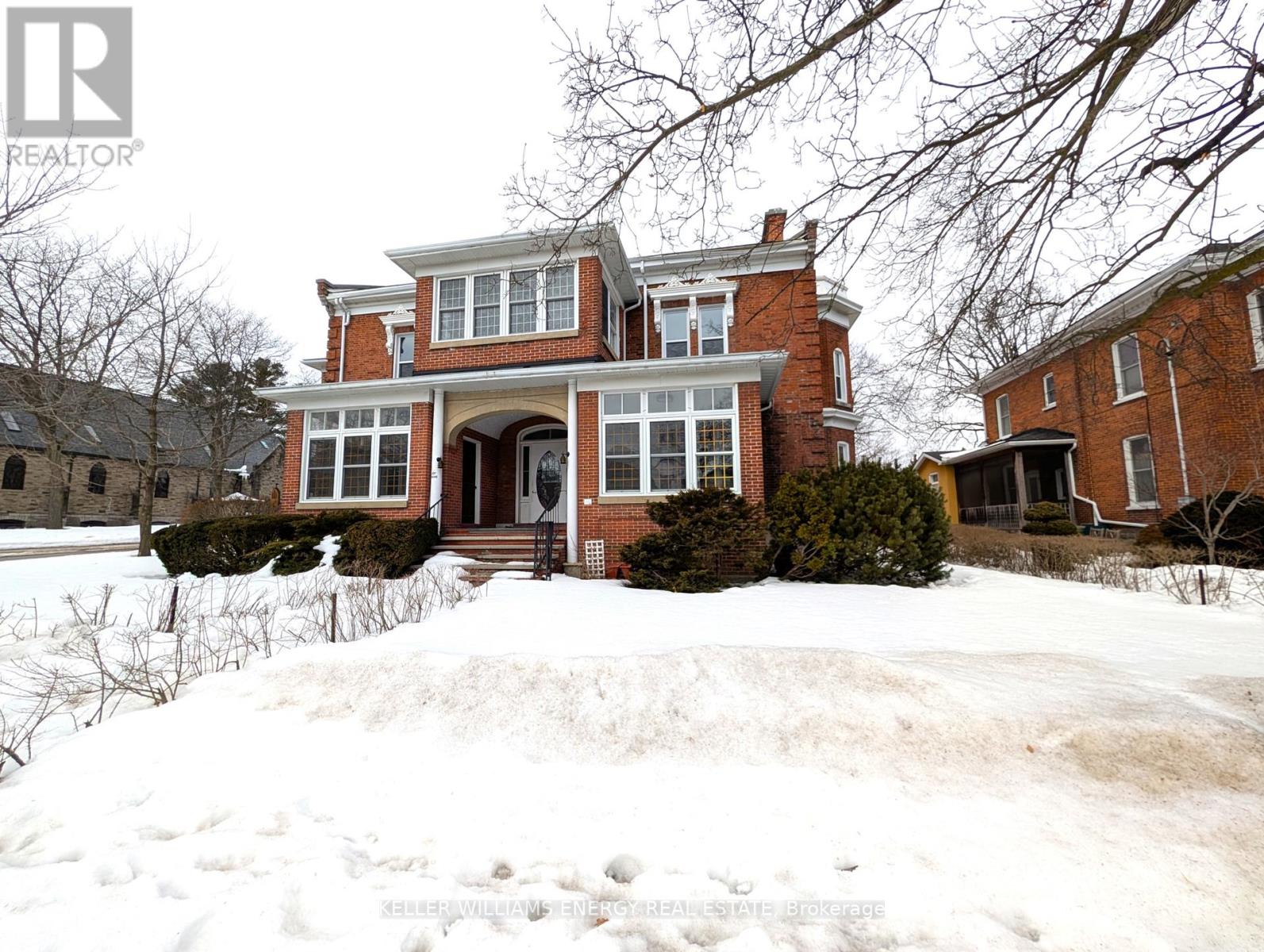 A large red brick house with a snow-covered front yard.