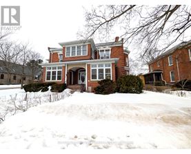 A large red brick house with a snow-covered front yard.
