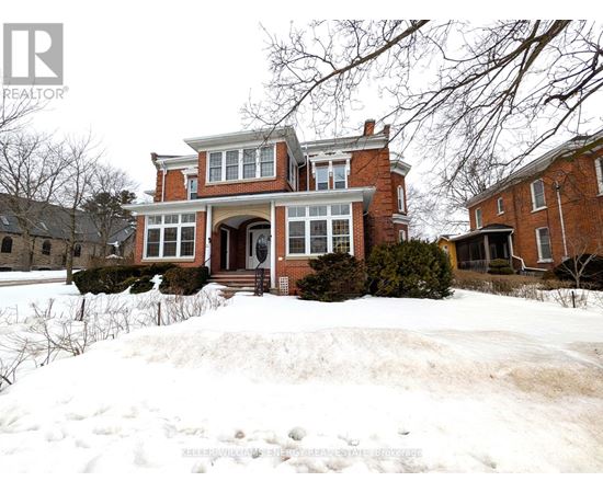 A large red brick house with a snow-covered front yard.