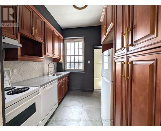 A kitchen with dark wood cabinets and white appliances.