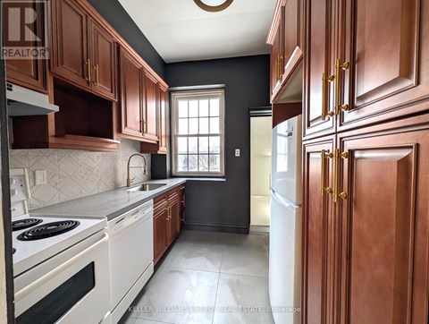 A kitchen with dark wood cabinets and white appliances.