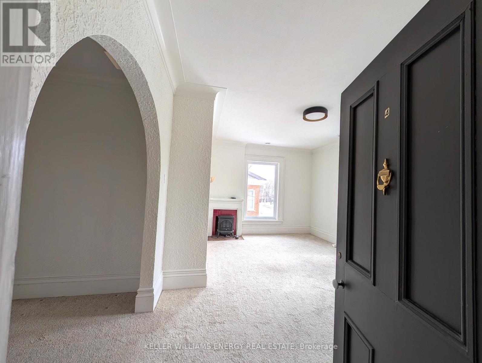 A room with a carpeted floor and a large arched doorway.
