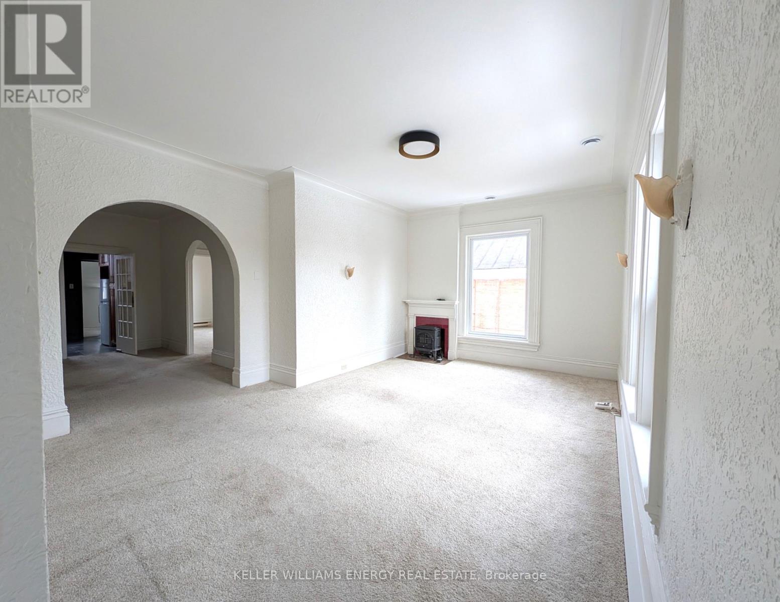 A spacious room with a carpeted floor and white walls.