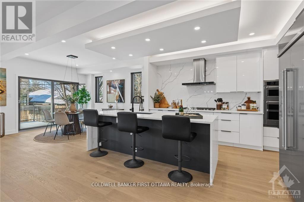 A modern kitchen with white cabinets and black bar stools.