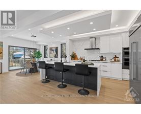 A modern kitchen with white cabinets and black bar stools.