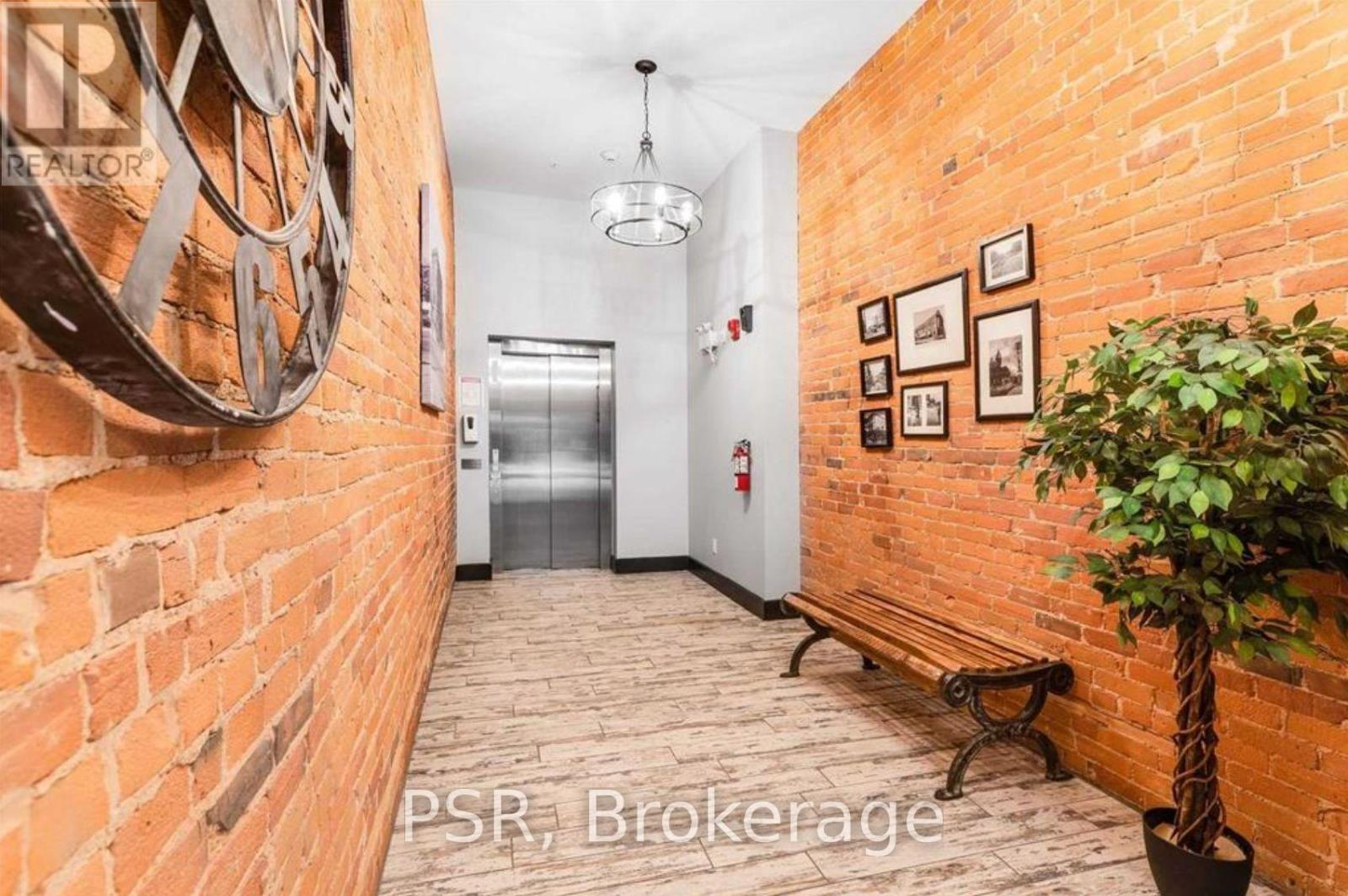 A hallway with a brick wall and a tree in a pot.