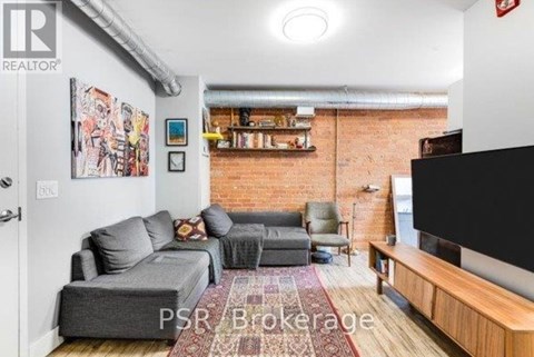 A living room with a grey couch and a red rug.