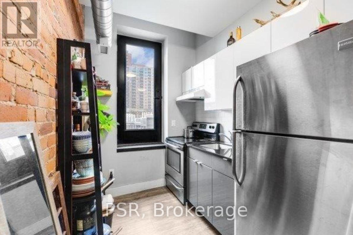 A modern kitchen with stainless steel appliances and a brick wall.