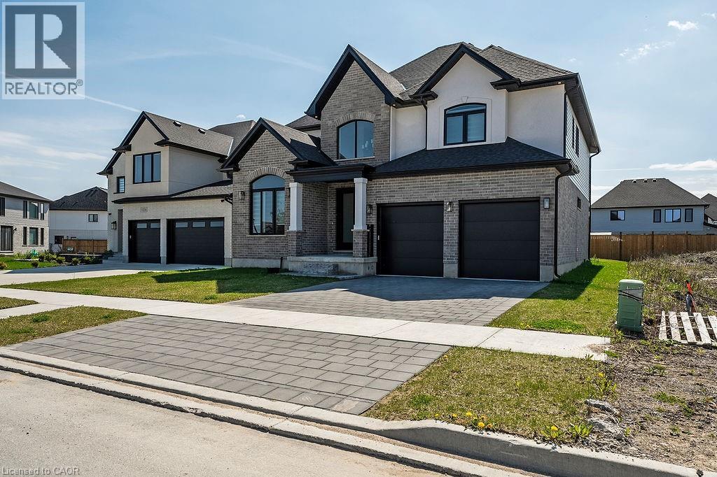 A large, modern house with a black garage door is for sale.
