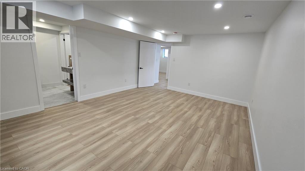 A spacious room with wooden flooring and white walls.